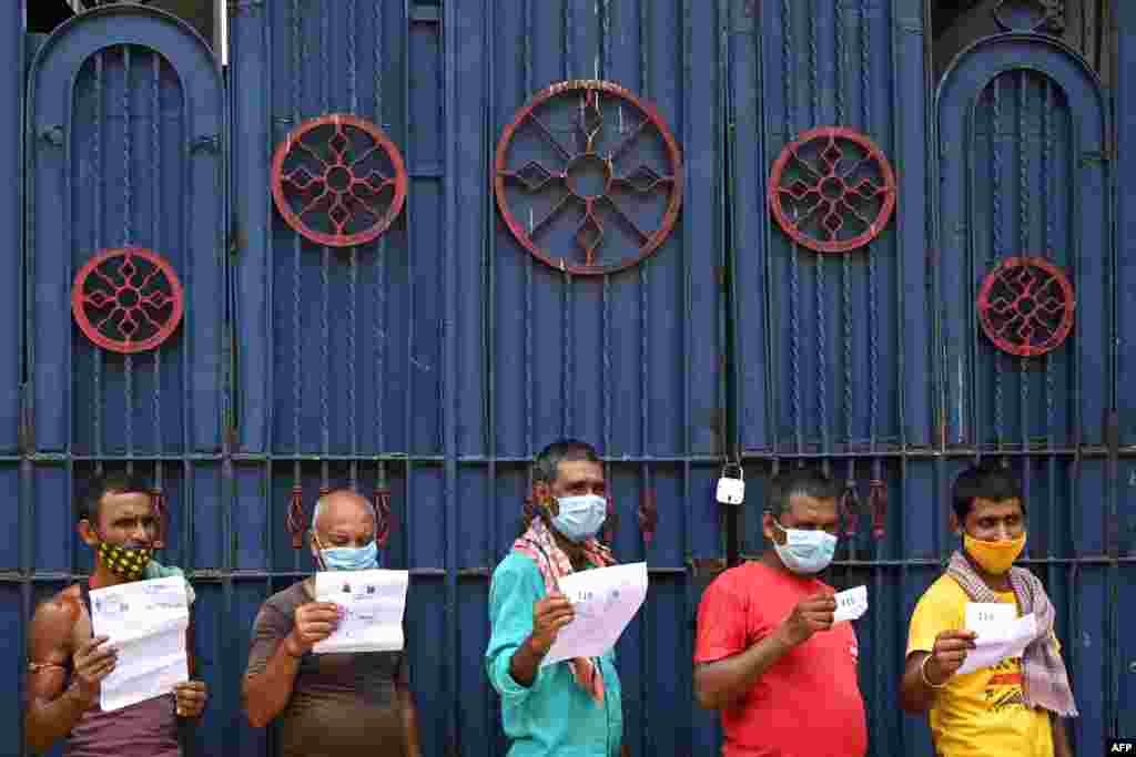 Workers hold documents as they wait for their turn to receive the first dose of Covishield vaccine in a passenger bus converted into a mobile vaccination center in Kolkata, India.