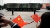 FILE - Onlookers wave Chinese flags as military vehicles carrying DF-41 ballistic missiles pass during a parade in Beijing, China, Oct. 1, 2019.