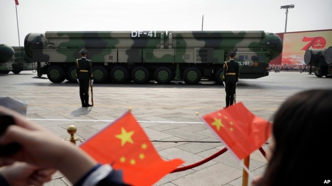 FILE - Onlookers wave Chinese flags as military vehicles carrying DF-41 ballistic missiles roll during a parade in Beijing, China, Oct. 1, 2019.