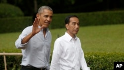 Former U.S. President Barack Obama, left, waves at reporters as he walks with Indonesian President Joko Widodo during their meeting at Bogor Presidential Palace in Bogor, West Java, Indonesia, June 30, 2017.