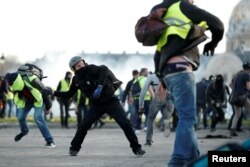 Protesters wearing yellow vests clash with French riot police near the Invalides during a demonstration of the "yellow vest" movement in Paris, Feb. 16, 2019.