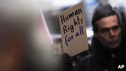 A protester holds a poster during a demonstration against racism and for human right for all people at the International Human Rights Day in Berlin, Dec. 10, 2011.