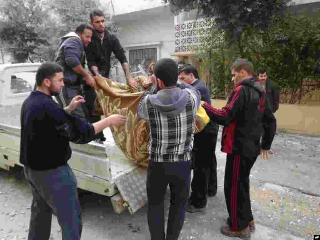People carry the body of man activists say was killed by the Syrian government army into a vehicle in the Sunni Muslim district of Bab Amro in Homs, February 9, 2012. (Reuters)