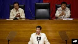 Philippine President Rodrigo Duterte, center, gestures as he is applauded by Senate President Vicente Sotto, left, and House Speaker Pantaleon Alvarez during his third State of the Nation Address at the House of Representatives in Quezon city, metropolitan Manila, Philippines Monday July 23, 2018.
