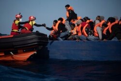 Migran dari Eritrea, Mesir, Suriah dan Sudan, dibantu oleh petugas dari LSM Spanyol Open Arms, setelah melarikan diri dari Libya dengan kapal kayu berbahaya di laut Mediterania, sekitar 110 mil sebelah utara Libya, Sabtu, 2 Januari, 2021.