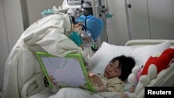  A girl infected with the new H7N9 bird flu strain draws a picture with a nurse at Ditan Hospital in Beijing, April 2013.
