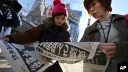 FILE - Japanese women react as they read extra newspapers in Tokyo reporting about an online video that purported to show an Islamic State group militant beheading Japanese journalist Kenji Goto, Sunday morning, Feb. 1, 2015. 