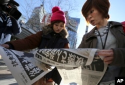 Japanese women react as they read extra newspapers in Tokyo reporting about an online video that purported to show an Islamic State group militant beheading Japanese journalist Kenji Goto, Feb. 1, 2015.