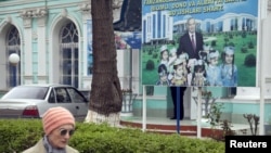 A woman walks past an election board of Uzbekistan's President and presidential candidate Islam Karimov near a polling station in Tashkent, March 29, 2015. 
