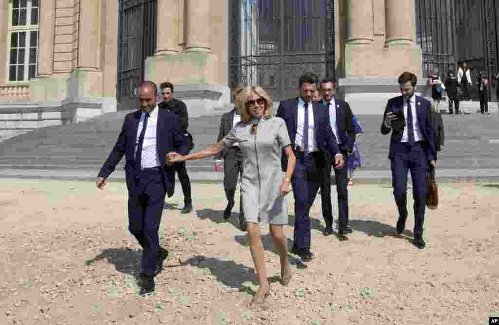 French first lady Brigitte Macron, center, walks in heels across the gravel to meet photographers during a NATO spouse program at the African Museum in Tervuren, Belgium.