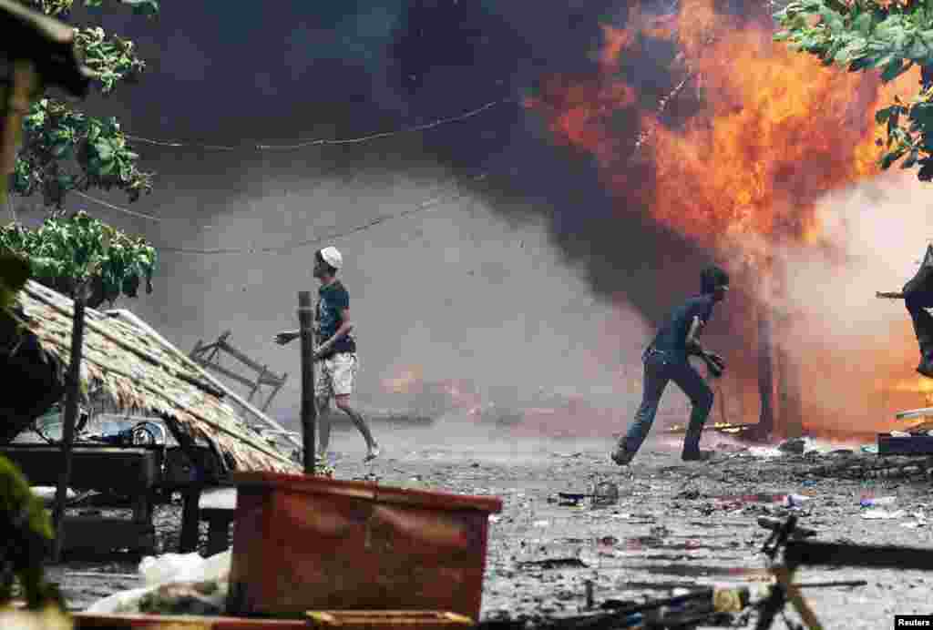 Rohingya men are seen among houses set on fire during fighting between Buddhist Rakhine and Muslim Rohingya communities in Sittwe, Burma, June 10, 2012.