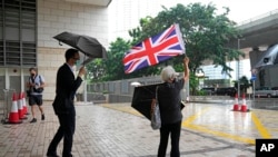 A pro-democracy activist holds the British flag as pro-democracy activists charged with subversion arrive for an appearance in court in Hong Kong, Sept. 23, 2021.