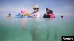 Retiree Madeline Barcelo (C) holds her granddaughter surrounded by relatives at the beach in Varadero, Cuba, Aug. 26, 2015. 