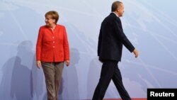 German Chancellor Angela Merkel and Turkey President Recep Tayyip Erdogan go their separate ways after a handshake greeting at the beginning of the G20 summit in Hamburg, Germany, July 7, 2017.