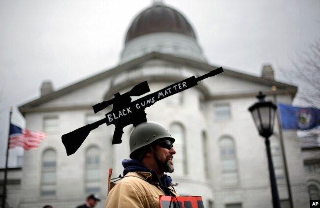 Joe Dobbins of Hartford, Maine, wears a cutout of an rifle while attending a gun rights rally, April 14, 2018, at the State House in Augusta, Maine.