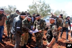 FILE - Turkey-backed Free Syrian Army fighters advance in Der Mismis village in the southeast portion of Afrin, Syria, March 13, 2018. Turkish troops and allied Syrian opposition fighters have intensified attacks on the Syrian Kurdish-held town of Afrin.