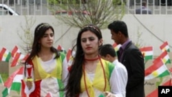 Kurdish girls dressed in the colors of their national flag stand behind graves of victims of the 1988 gas attacks during a ceremony marking the anniversary of the attacks in the Iraqi northern Kurdish town of Halabja, 16 Mar 2010