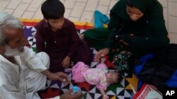 Family members surround a child suffering from dehydration due to severe heat, at a local hospital in Karachi, Pakistan, June 23, 2015.