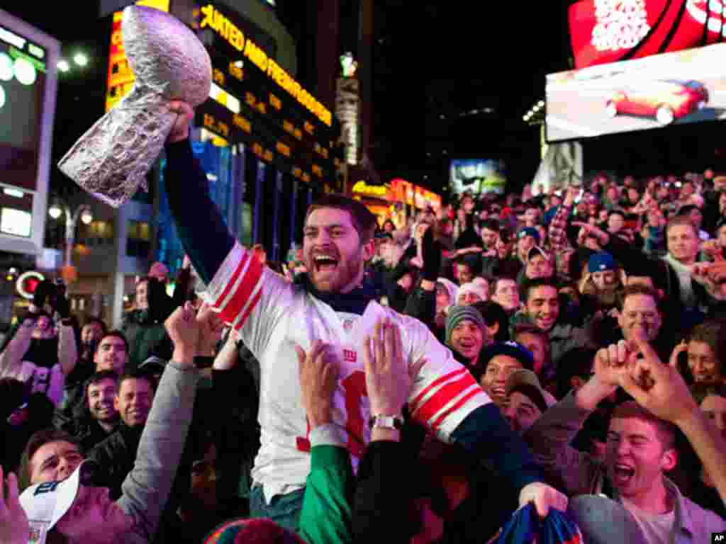 Tom Amendola, of Secaucus, New Jersey, celebrates a New York Giants win against the New England Patriots in the NFL football Super Bowl with a homemade trophy in Times Square, New York on February 5, 201. (AP)
