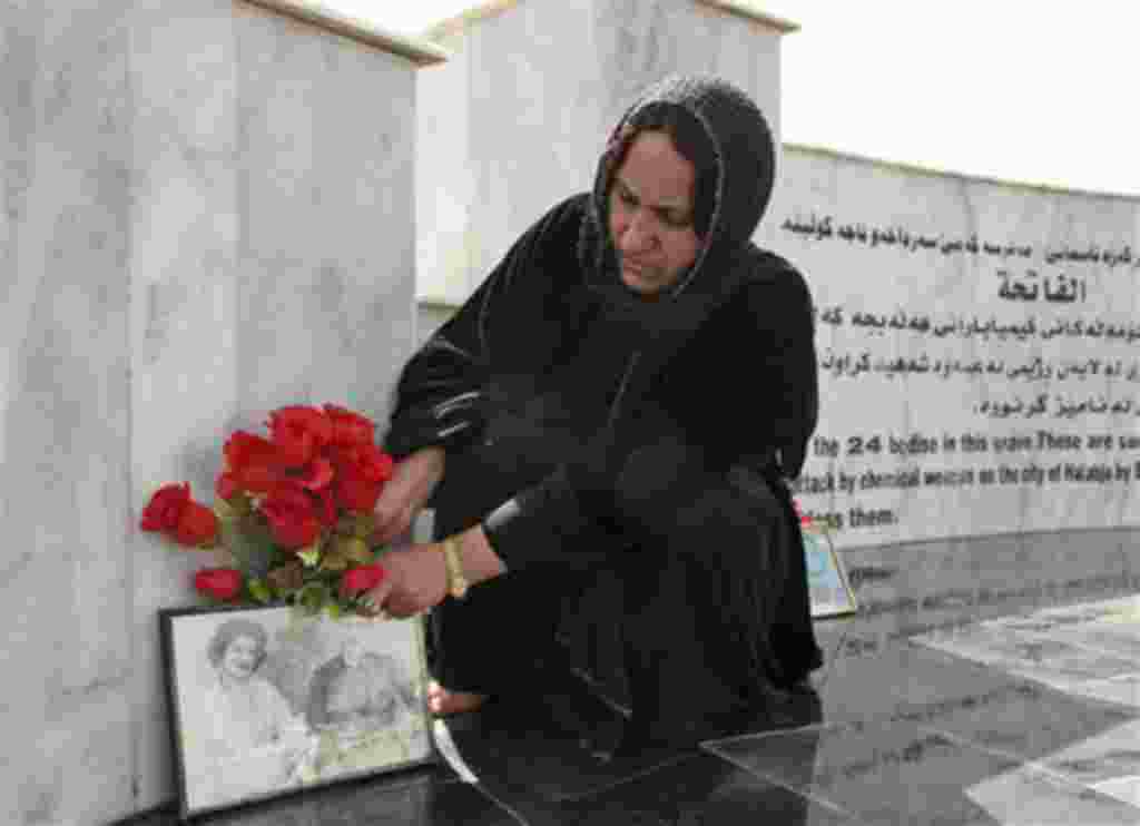 Kurdish woman lays flowers at a monument for the victims of Halabja massacre on its 20th anniversary in Halabja, Iraq , Sunday, March 16, 2008. Some 5,600 people were killed when Saddam Hussein ordered the attack in Halabja as part of a scorched-earth cam