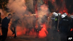 Montenegrin police officers are engulfed in smoke and flames as opposition supporters hurl torches toward them during a protest in front of the parliament building in Podgorica, Montenegro, Oct. 24, 2015.