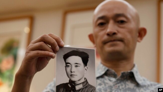 2020年10月16日武汉新冠肺炎死者的亲属张海拿着他病逝的父亲年轻时拍摄的照片。