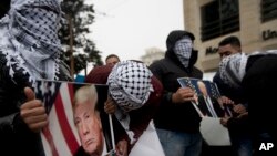 Palestinians holds posters of the U.S. President Donald Trump during a protest in the West Bank City of Ramallah, Dec. 6, 2017. 