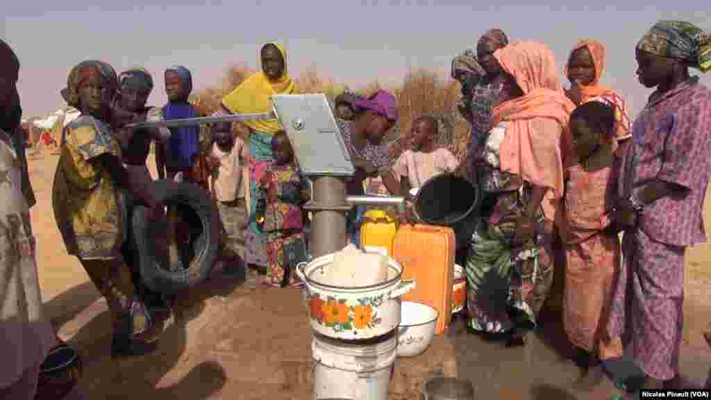 Des femmes et des enfants tirent de l'eau du puits dans le camp Assaga, à Diffa, au Niger, le 3 mars 2016. (VOA/Nicolas Pinault)