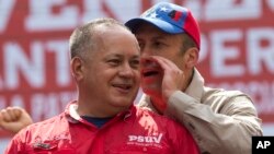 Pemimpin Partai Sosialis Venezuela Diosdado Cabello, kiri, mendengarkan bisikan Wakil Presiden Venezuela Tareck El Aissami saat protes menentang AS di Caracas, Venezuela, 28 Maret 2017.