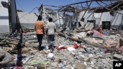 FILE - Debris covers the ground after an airstrike at a detention center in Tajoura, east of Tripoli in Libya, July 3, 2019.