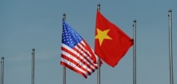 The U.S. flag (L) flutters next to the Vietnamese flag in Hanoi, Vietnam June 1, 2015.