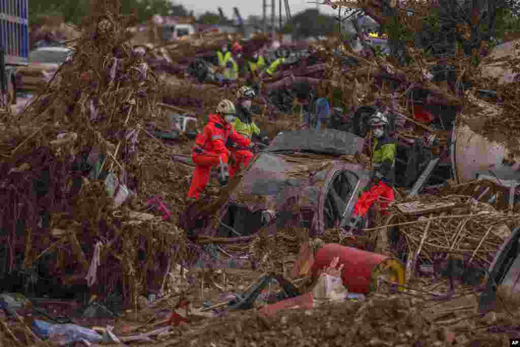 Petugas layanan darurat memindahkan mobil-mobil yang terperosok lumpur di daerah yang terkena banjir di Catarroja, Spanyol. (AP)&nbsp;