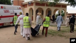 FILE - Rescue workers remove a body after a suicide attack at a camp of people displaced by Islamist extremists in Maiduguri, Nigeria, July 24, 2017. Female suicide bombers attacked two displaced persons camps in northeastern Nigeria's main city.