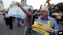 A taxi driver holds a sign that says in Spanish "Uber (equals) job loss" as he and other cabbies block a main avenue in Buenos Aires, Argentina, April 12, 2016.