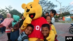 Anak-anak penyintas bencana memeluk relawan yang mengenakan kostum Winnie the Pooh saat mengikuti program penyembuhan trauma di tempat penampungan di Palu, Sulawesi Tengah, 8 Oktober 2018.