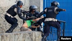 Policías venezolanos capturan a un manifestante en Caracas.