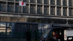 资料照片：一名送货员驾车经过位于北京的日本驻华大使馆。2025年11月24日)