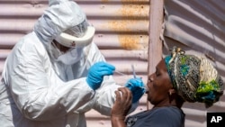 A woman opens her mouth for the heath worker to collect a sample for coronavirus testing during the screening and testing campaign aimed to combat the spread of COVID-19 at Lenasia South, south Johannesburg, South Africa, Tuesday, April 21, 2020. …