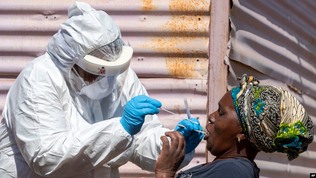 FILE - A woman opens her mouth for the heath worker to collect a sample for coronavirus testing during the screening and testing campaign aimed to combat the spread of COVID-19 at Lenasia South, south Johannesburg, South Africa, April 21, 2020.