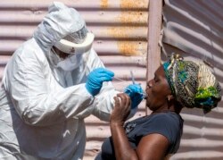 A woman opens her mouth for the heath worker to collect a sample for coronavirus testing during the screening and testing campaign aimed to combat the spread of COVID-19 at Lenasia South, south Johannesburg, South Africa, April 21, 2020.
