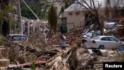 People walk next to rubble and damaged trees in the aftermath of Hurricane Otis, in Acapulco, Mexico, Oct. 29, 2023.