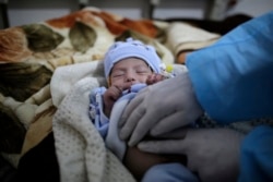 FILE - A doctor checks two-month-old Mujahed Ali, suffering from a cholera infection, at Al-Sabeen hospital, in Sanaa, Yemen, Mar. 30, 2019.