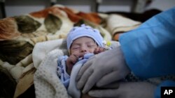 FILE - A doctor checks two-month-old Mujahed Ali, suffering from a cholera infection, at Al-Sabeen hospital, in Sanaa, Yemen, Mar. 30, 2019. 