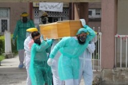 FILE - Health workers wearing protective gear move a body of a man who died from the coronavirus disease (COVID-19), outside an isolation ward at the Ayub Teaching Hospital in Abbottabad, Pakistan, April 16, 2020.