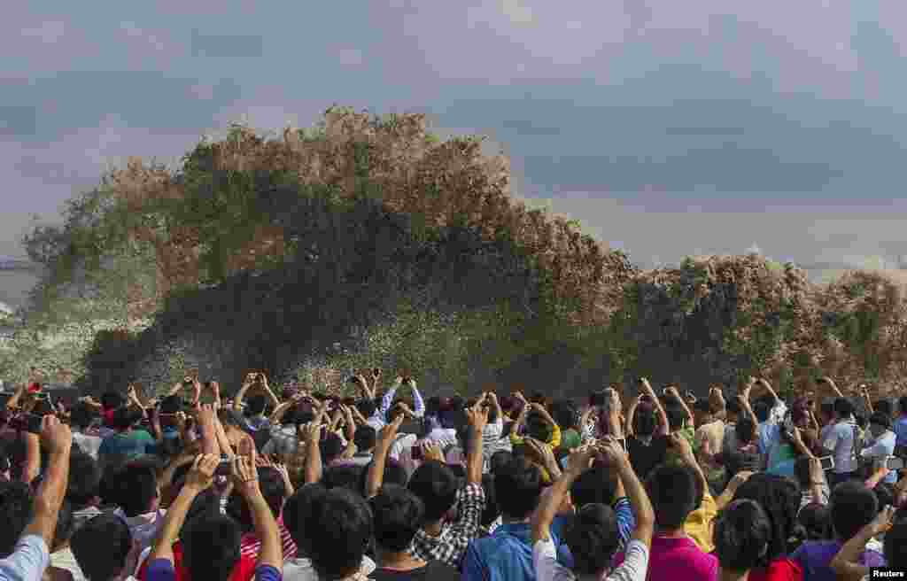 Para pengunjung mengambil gambar gelombang pasang akibat Topan Usagi di kota Hangzhou, provinsi Zhejiang, China.