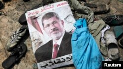 A poster of deposed Egyptian president Mohamed Morsi lies amid debris of a cleared protest camp of his supporters in Cairo, Aug. 15, 2013.