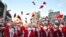 South Korean volunteers in Santa Claus outfits throw Santa hats during a ceremony before the delivery of Christmas gifts in Seoul.
