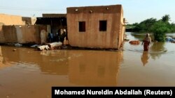 FILE: Residents walk through floodwaters from the Blue Nile as it submerges their neighborhood in the Al-Ikmayr area of Omdurman in Khartoum, Sudan Taken 8.27.2020