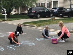 Family members write chalk messages to their neighbors as they stay at home during the coronavirus outbreak, in Glen Allen, Va., March 26, 2020.