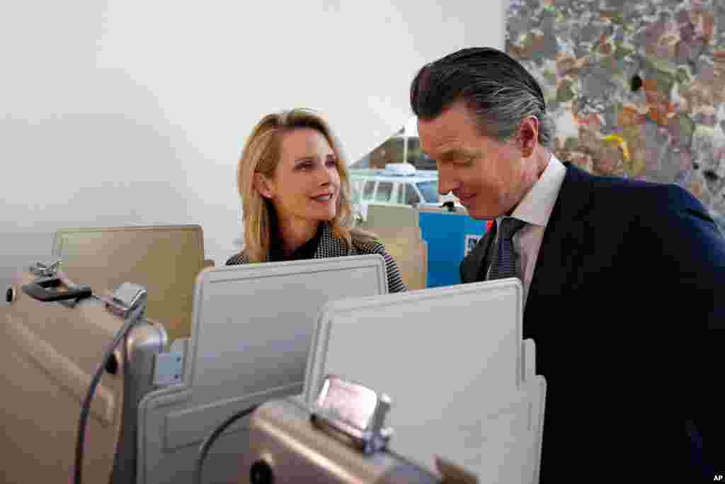 California Gov. Gavin Newsom looks over the ballot of his wife, First Partner Jennifer Siebel Newsom, as they vote on Super Tuesday in Sacramento, Calif., March 3, 2020. 